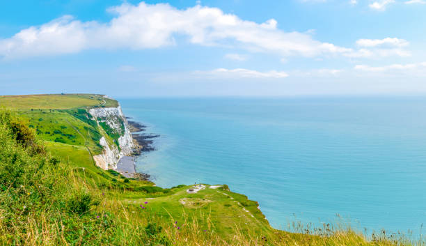 White Cliffs of Dover, Kent, UK: Two people standing on a hilltop, looking out over The White Cliffs of Dover.

The White Cliffs of Dover are the region of English coastline facing the Strait of Dover and France. The cliff face, which reaches a height of 350 feet (110 m). The cliffs, on both sides of the town of Dover in Kent, stretch for eight miles (13 km).